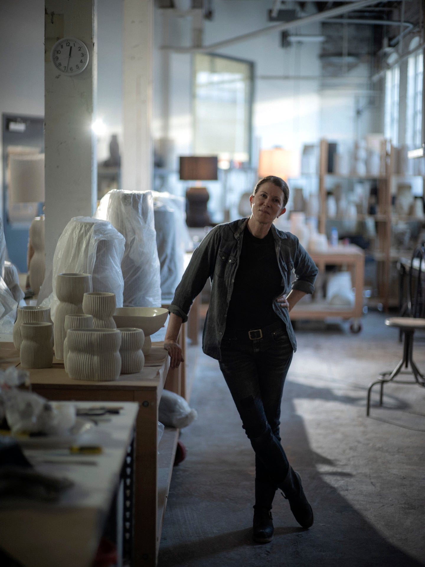 Woman in pottery studio, surrounded by ceramics
