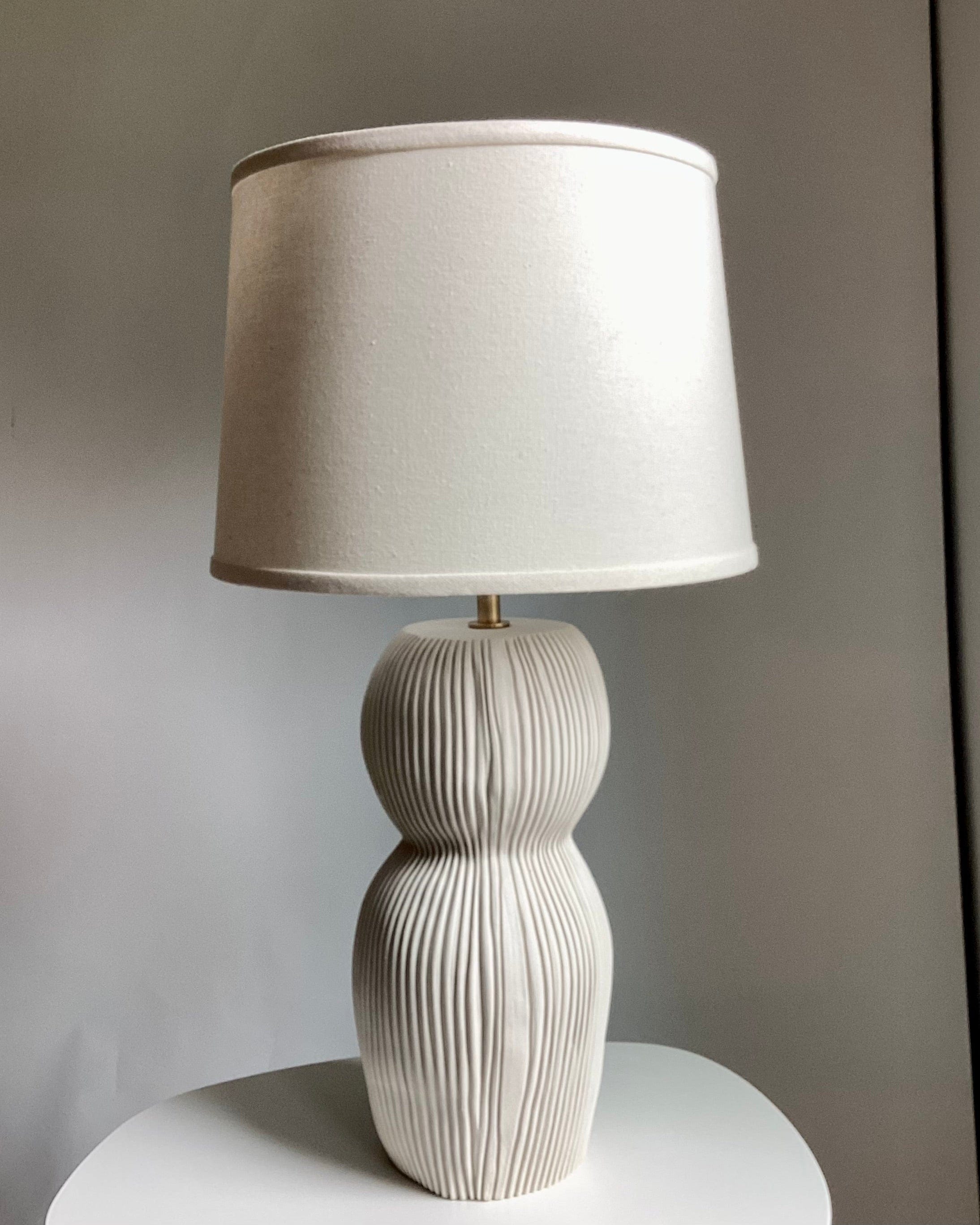 Beige table lamp with a textured base and lampshade.