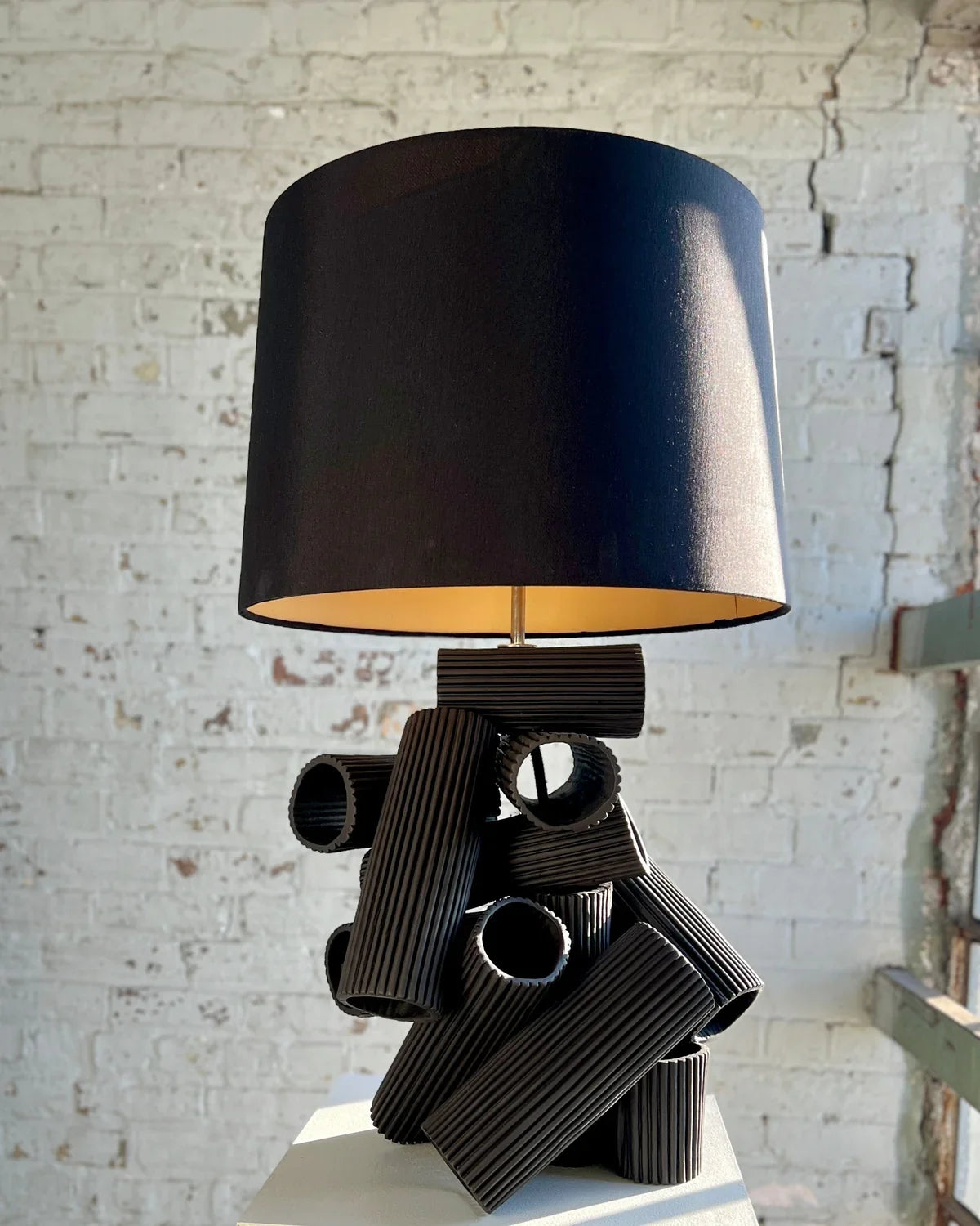 Black lamp with cylindrical shade and unique base.