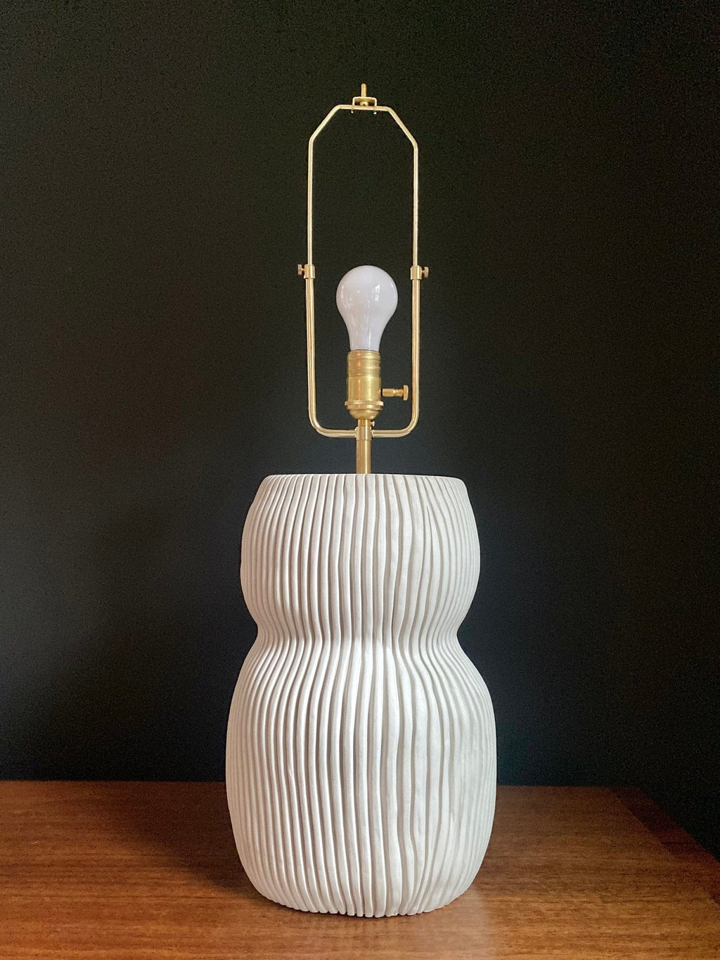 White ribbed ceramic lamp with lightbulb.