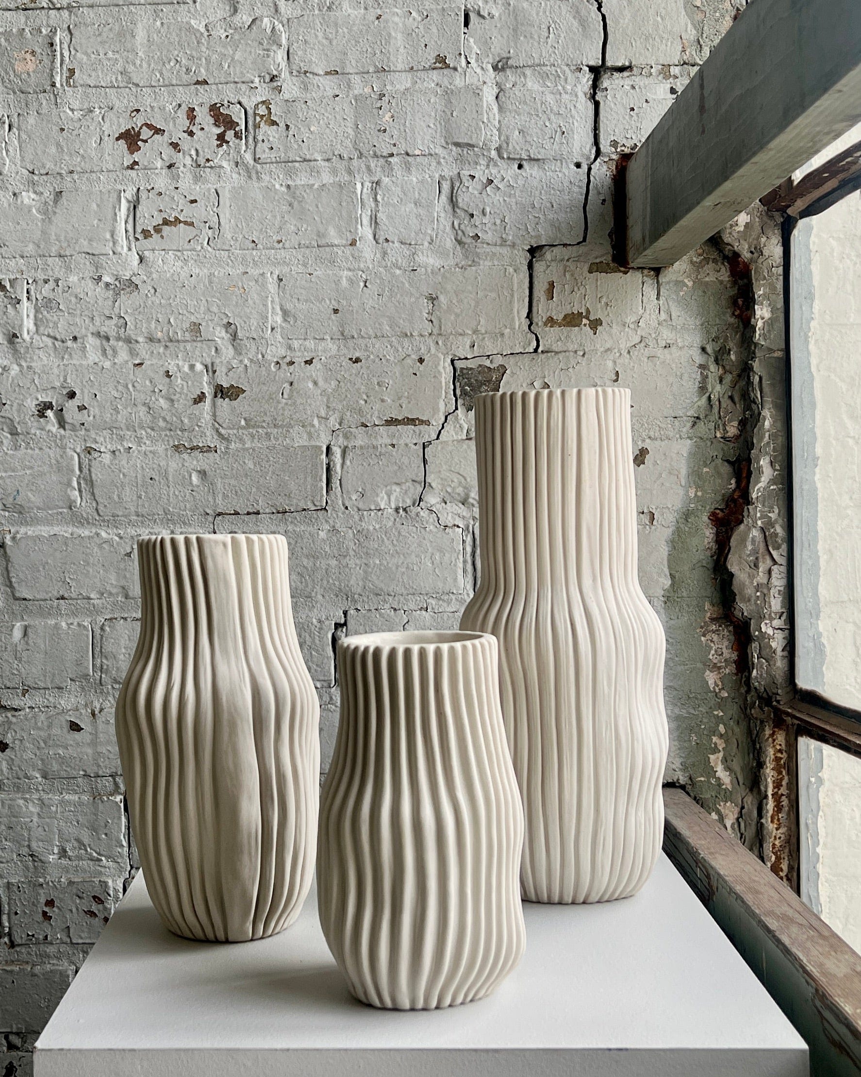 Set of three textured vases on display