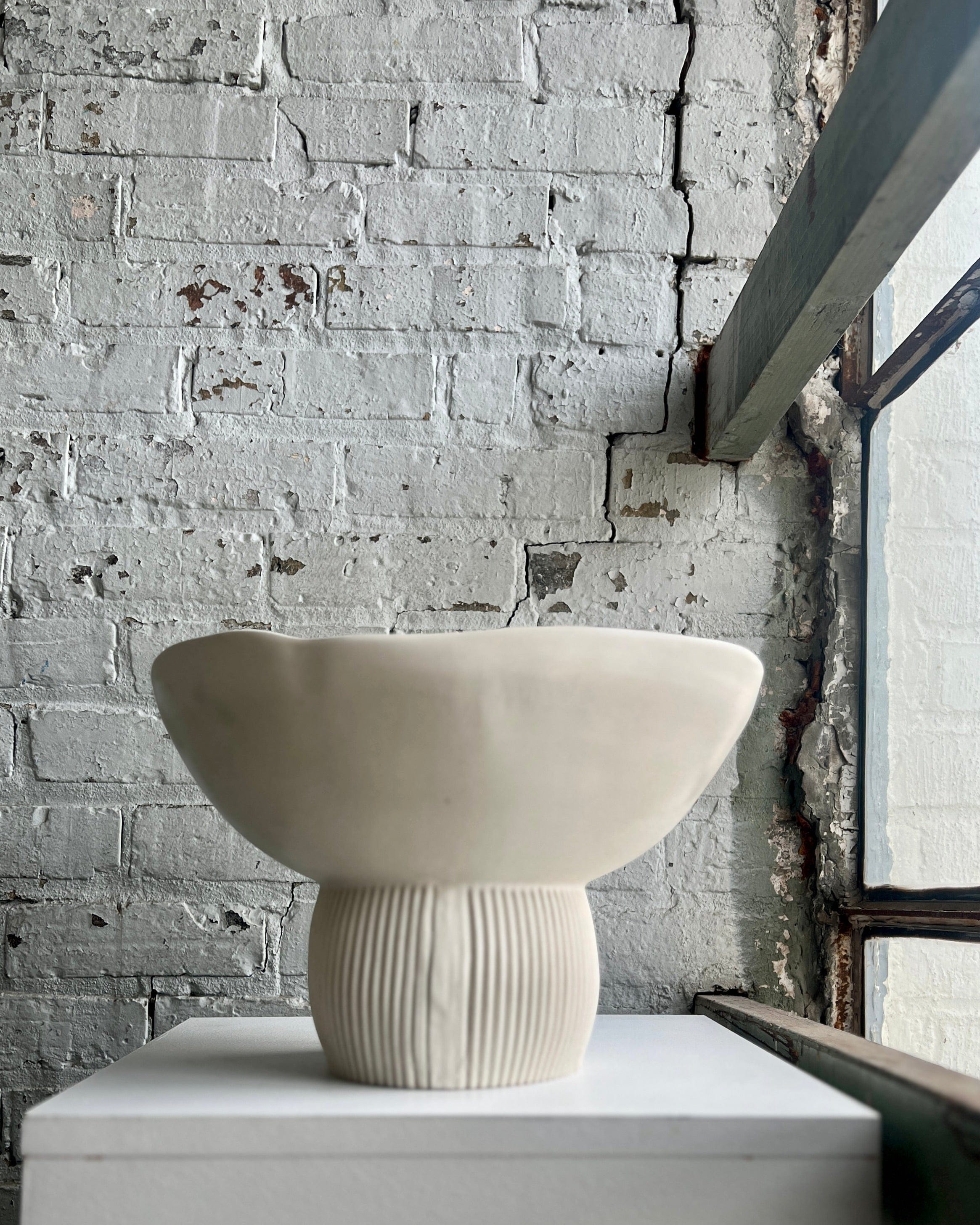 Ceramic pedestal bowl on white surface, product image