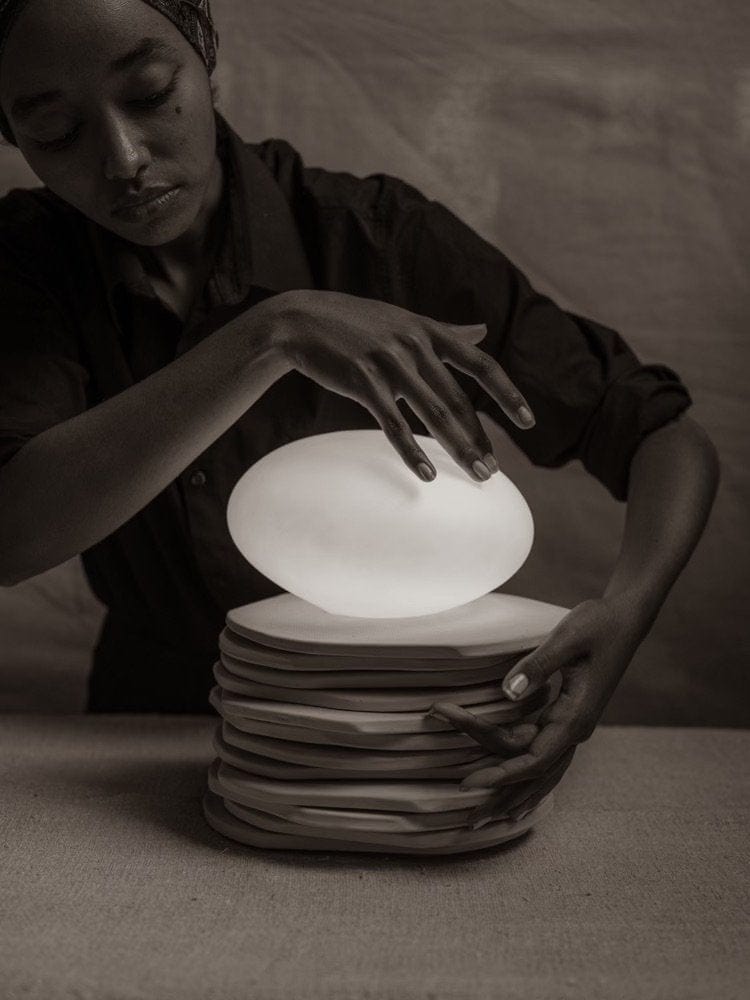 Woman arranging stacked plates with glowing orb.