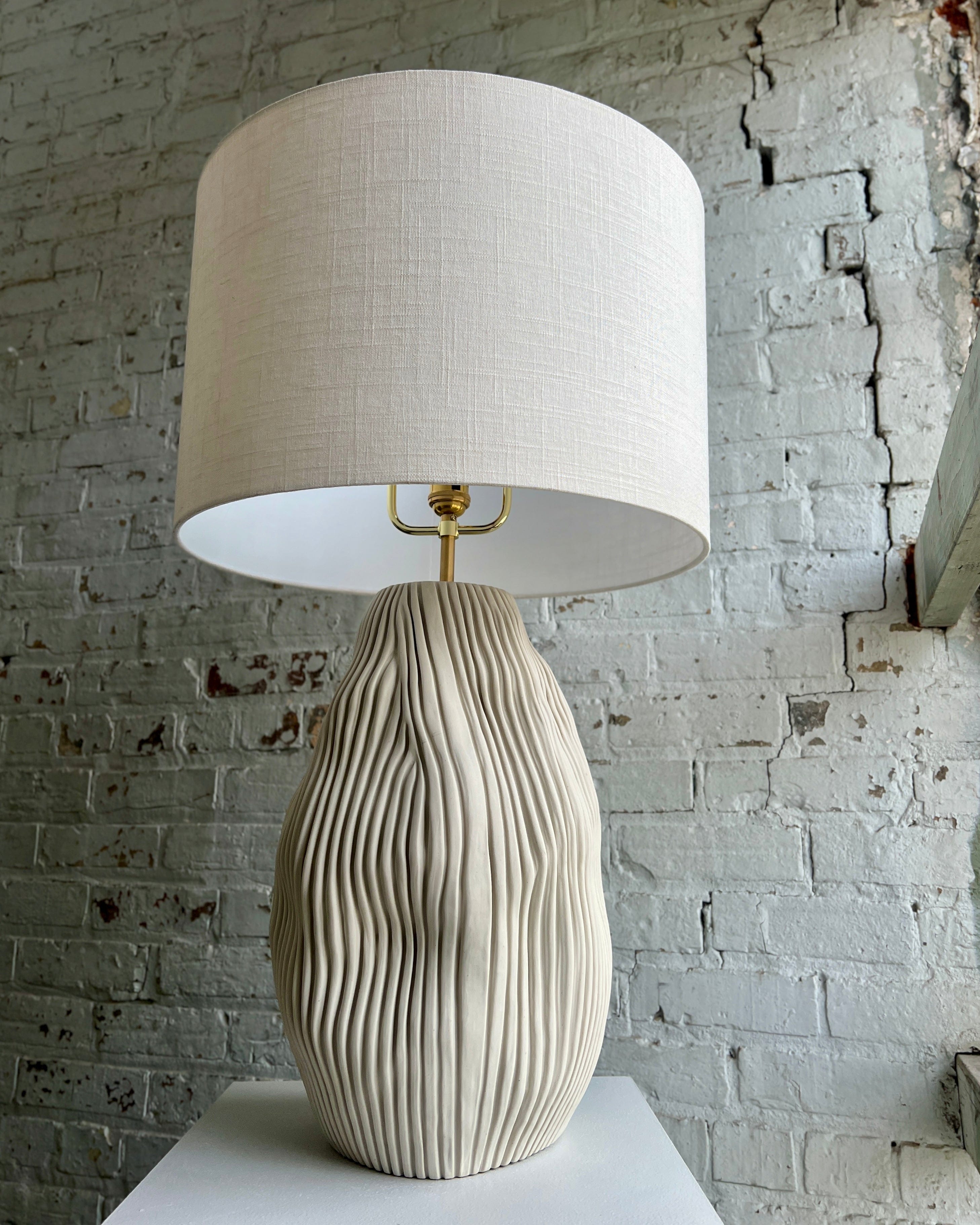 Table lamp with beige shade and textured base.