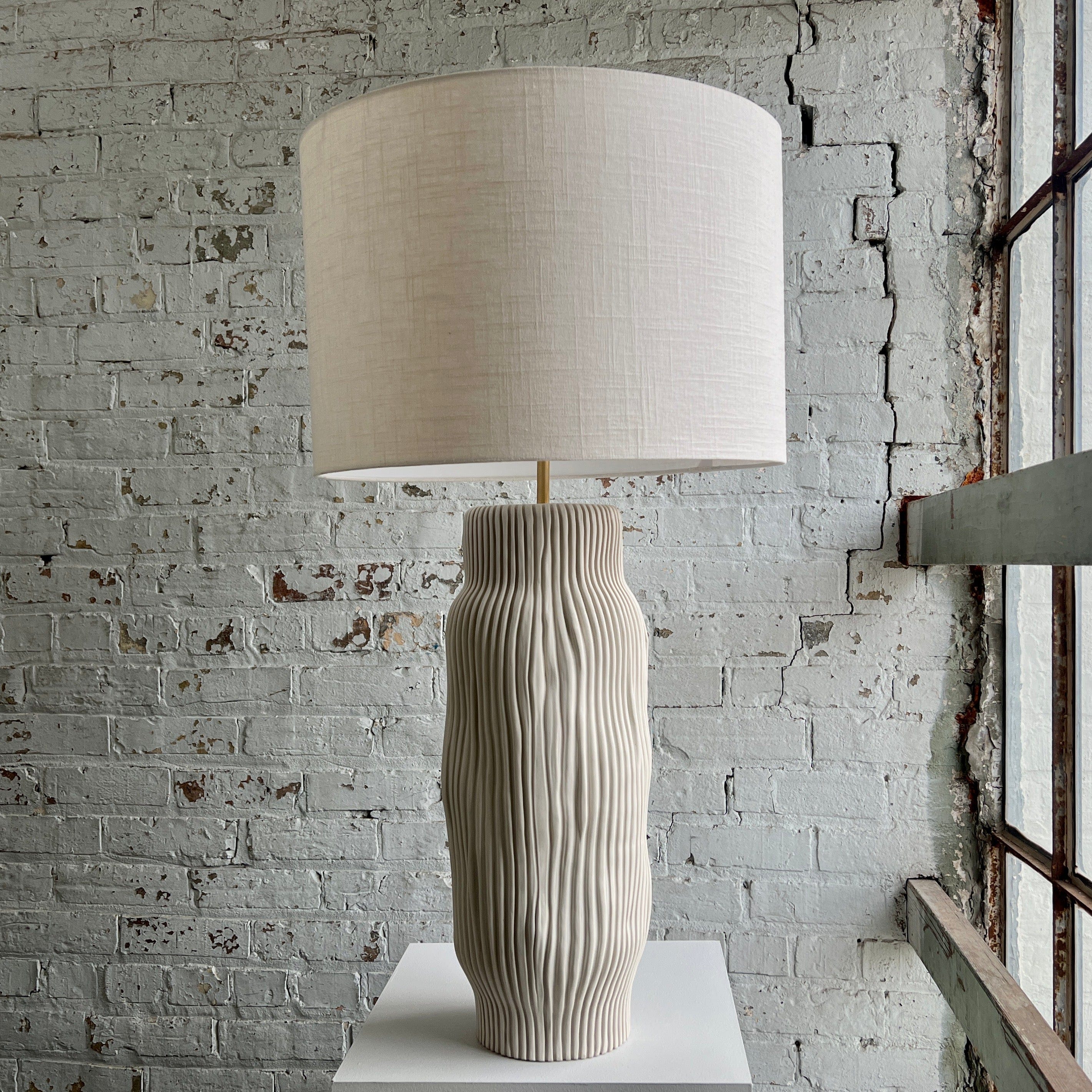 Tall lamp with beige shade and textured base.
