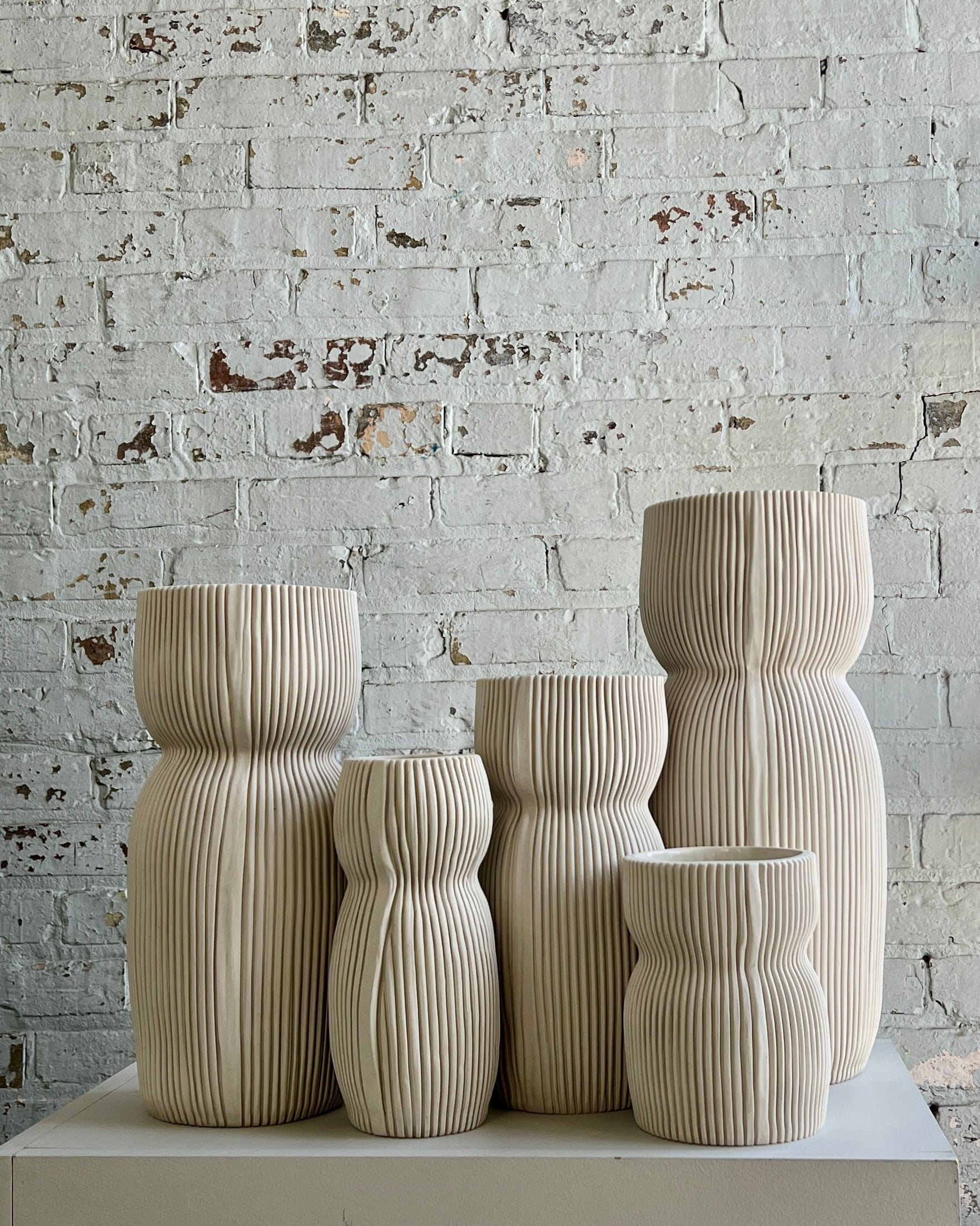 Five beige, ribbed, ceramic vases.