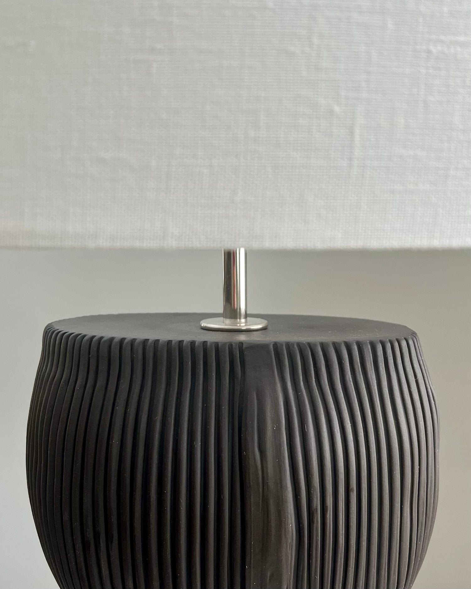 Black lamp with textured base and white lampshade.