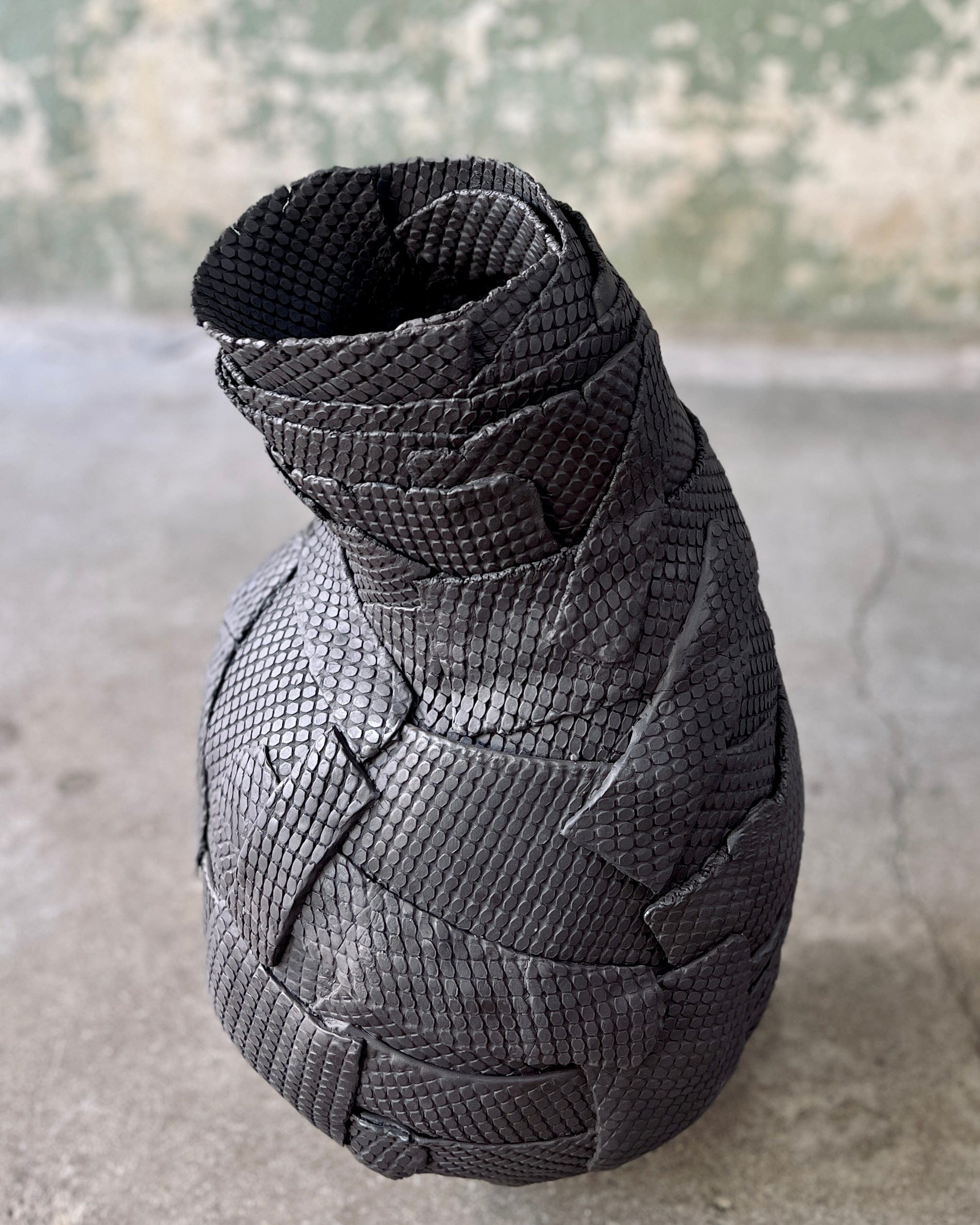 Black textured vase with a curved neck.