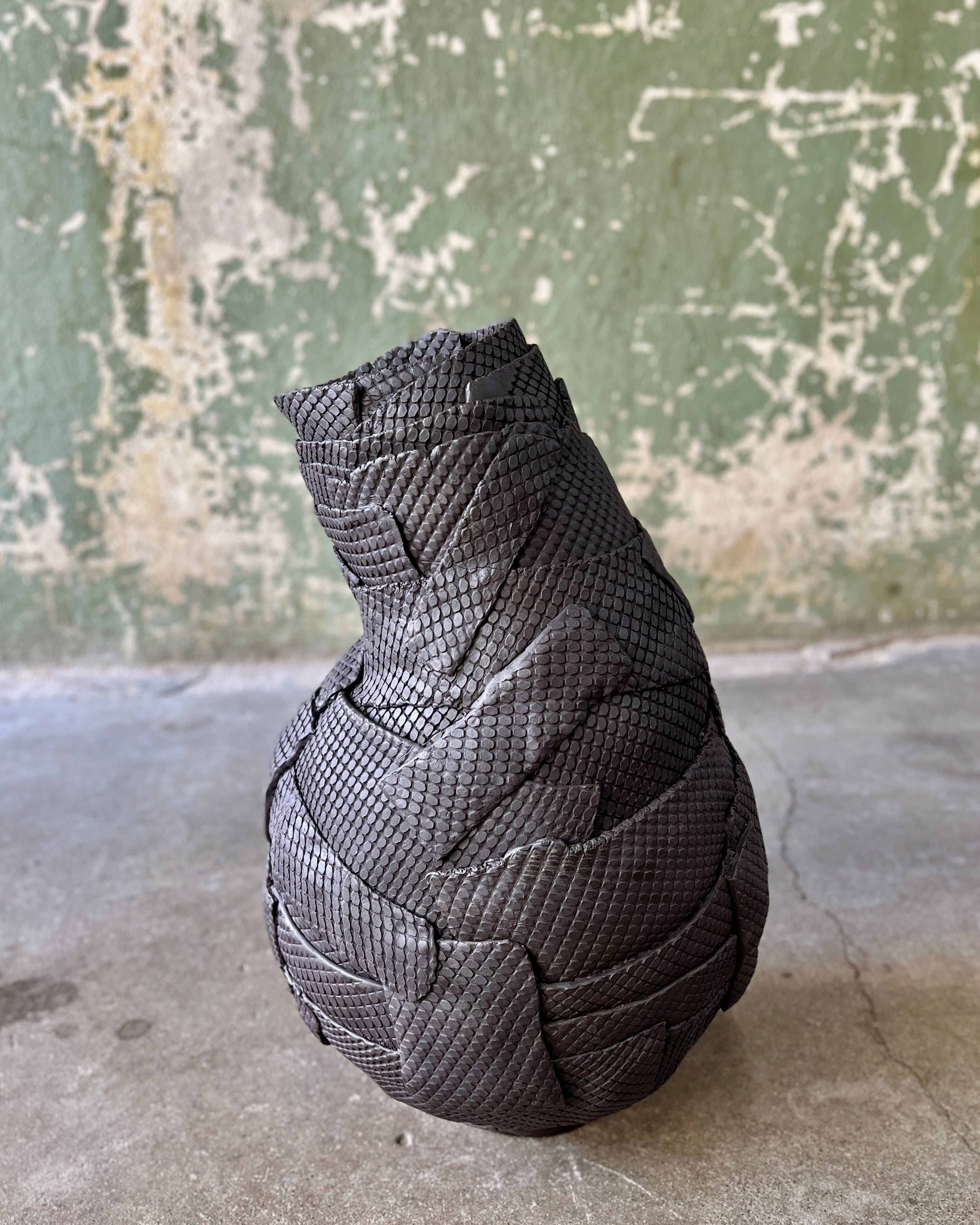 Black textured sculpture on a concrete surface.